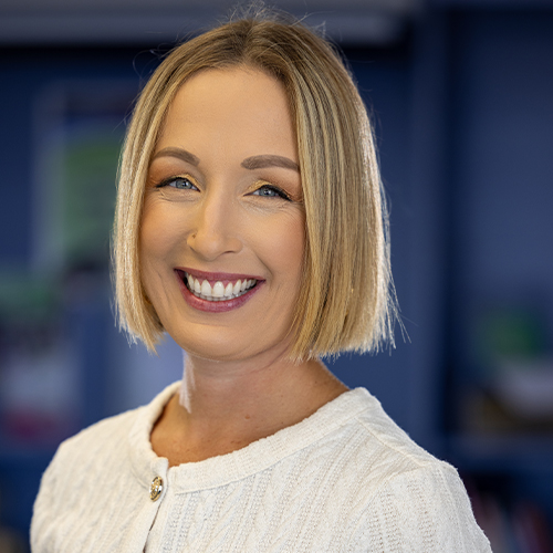 Blonde woman smiling while wearing a white top