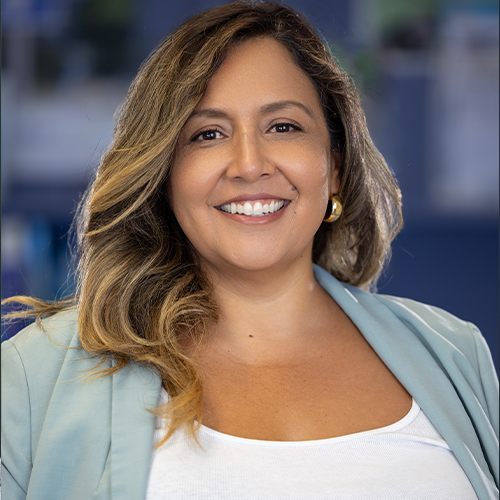 Women with brown hair and a light teal blazer smiling