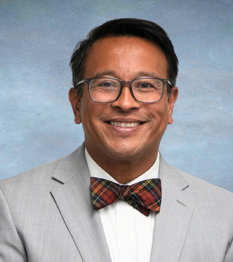 Dr. Jose M. Mata, Ed.D. wearing a grey suit with a white dress shirt and a plaid bow tie