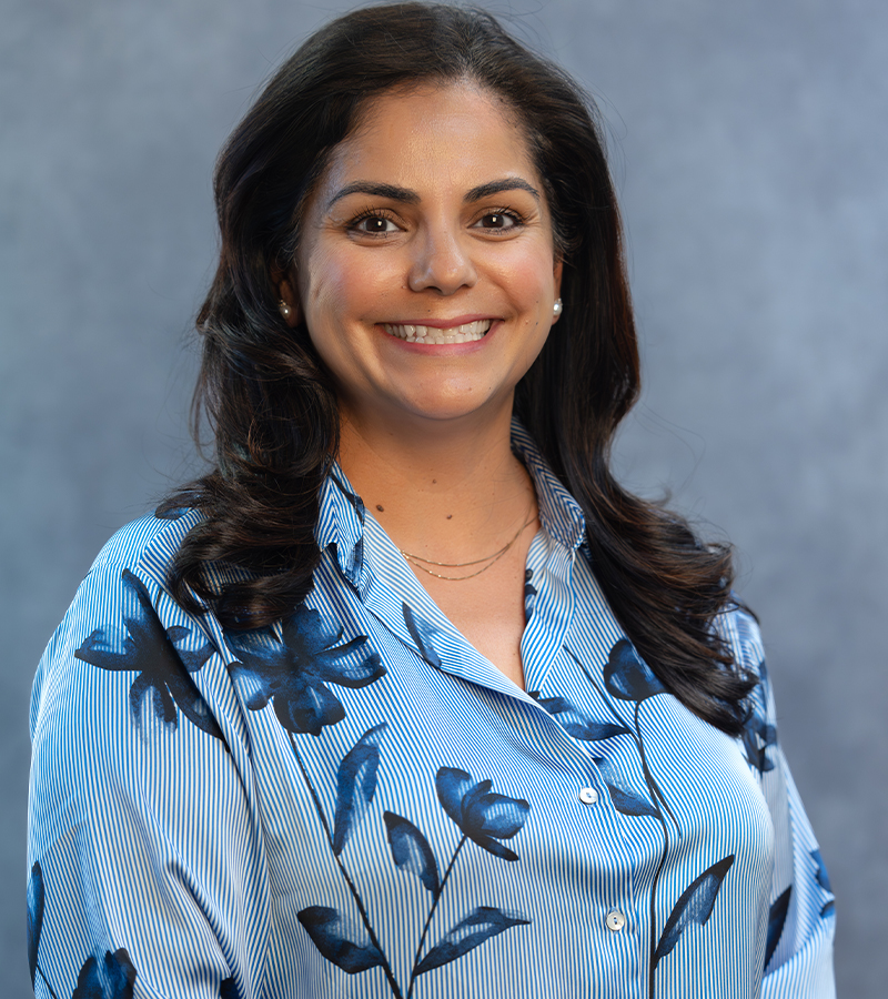 Monica Garcia wearing a blue blouse posing in front of a blue background